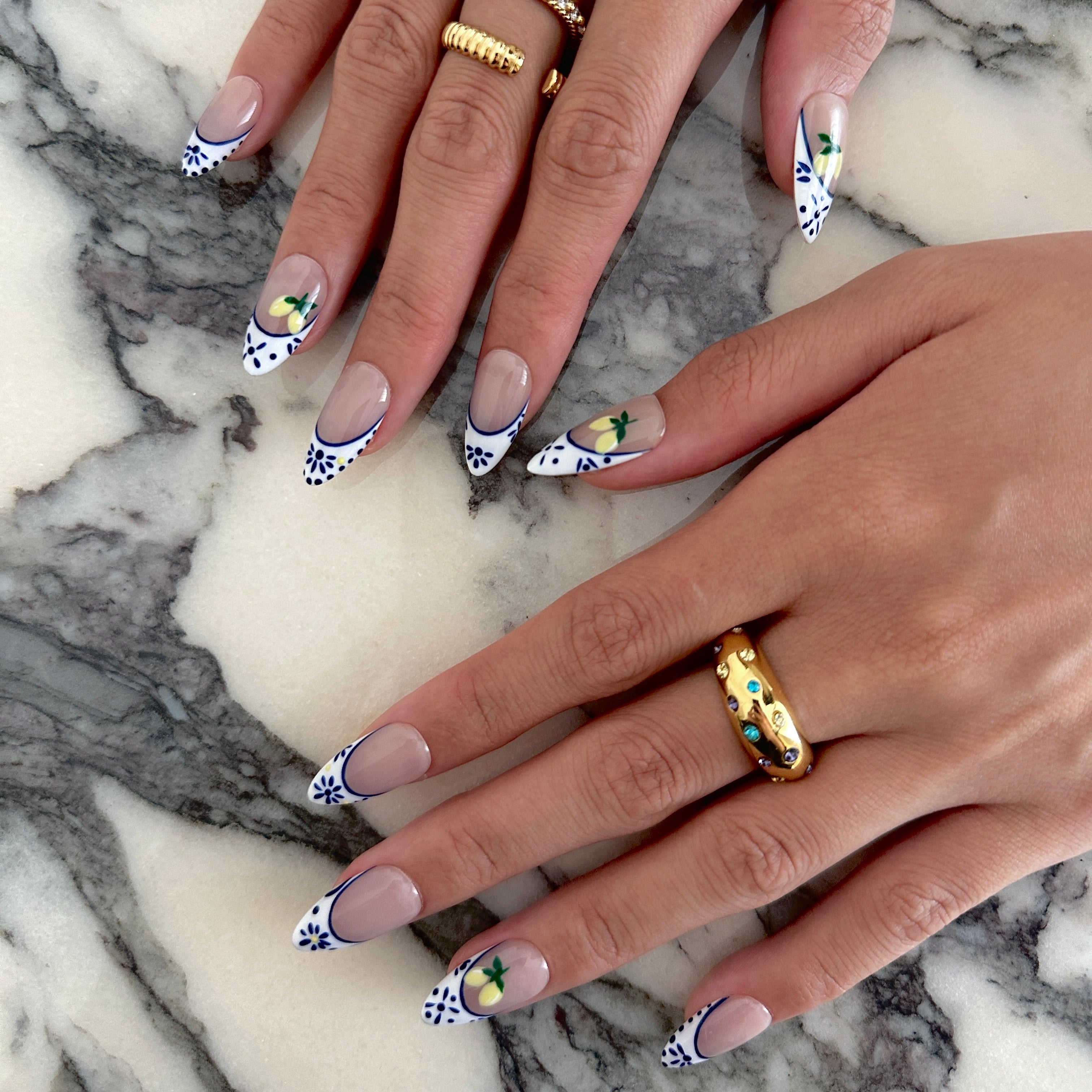 Close-up of hands with decorative nail art on a marble surface