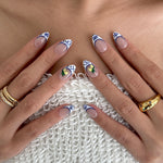 Close-up of hands with decorative nail art on a textured surface