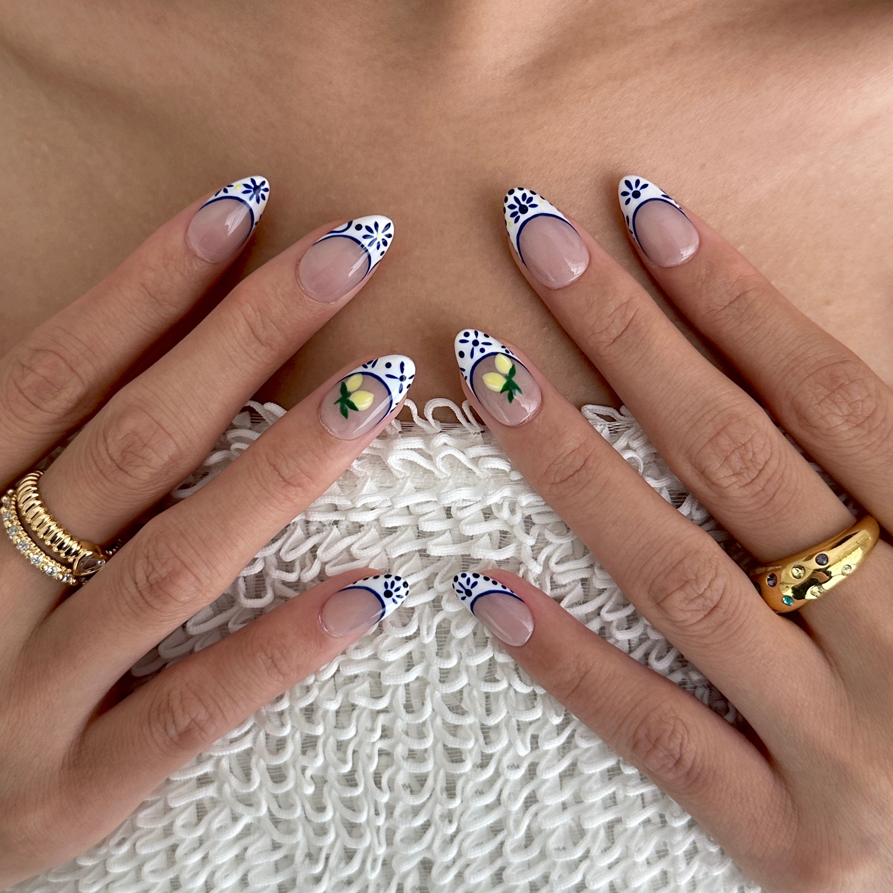 Close-up of hands with decorative nail art on a textured surface