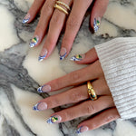 Close-up of hands with decorative nail art on a marble surface