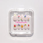 Set of decorative press-on nails with floral designs in a clear plastic case on a white background.