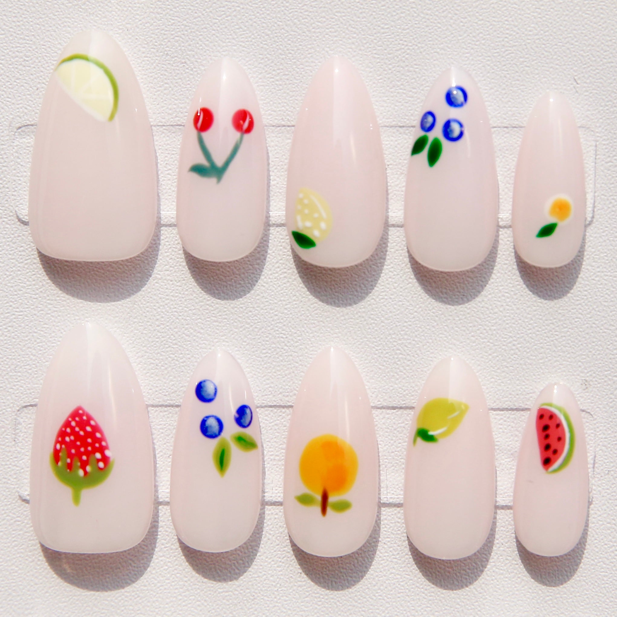 Set of white nail art designs with colorful floral and fruit patterns on a white background