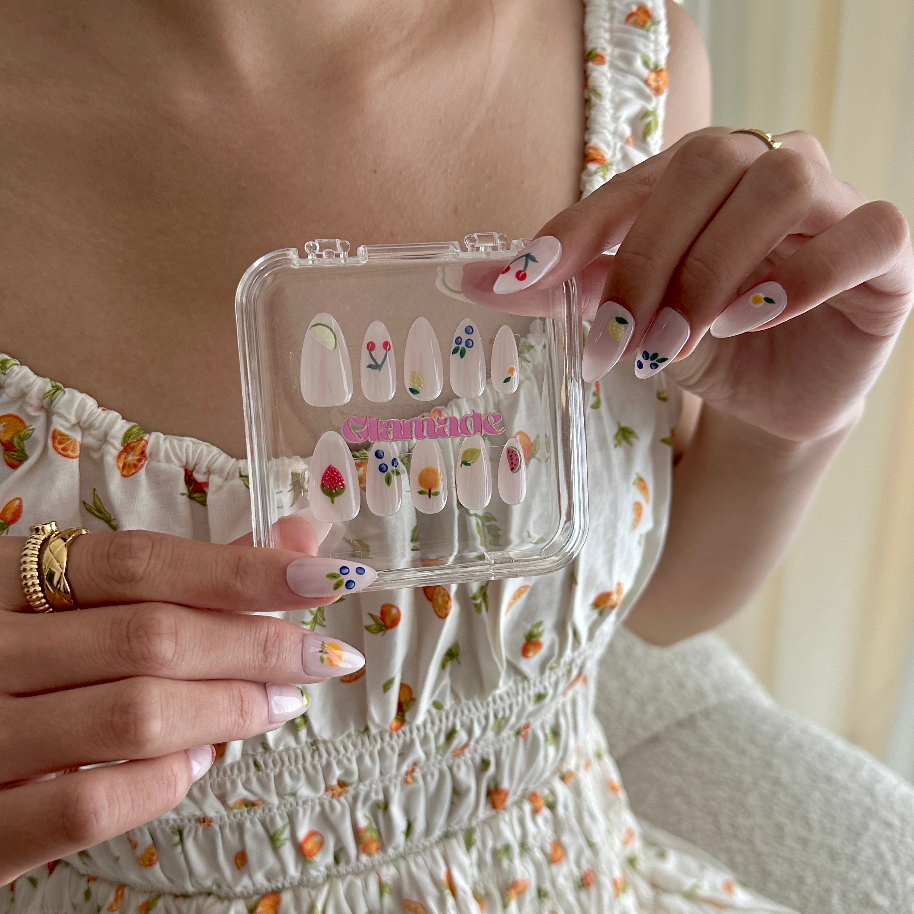 Person holding a clear nail art kit with floral designs and handmade nails.
