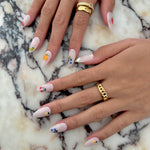 Close-up of hands with decorative nail art on a marble surface