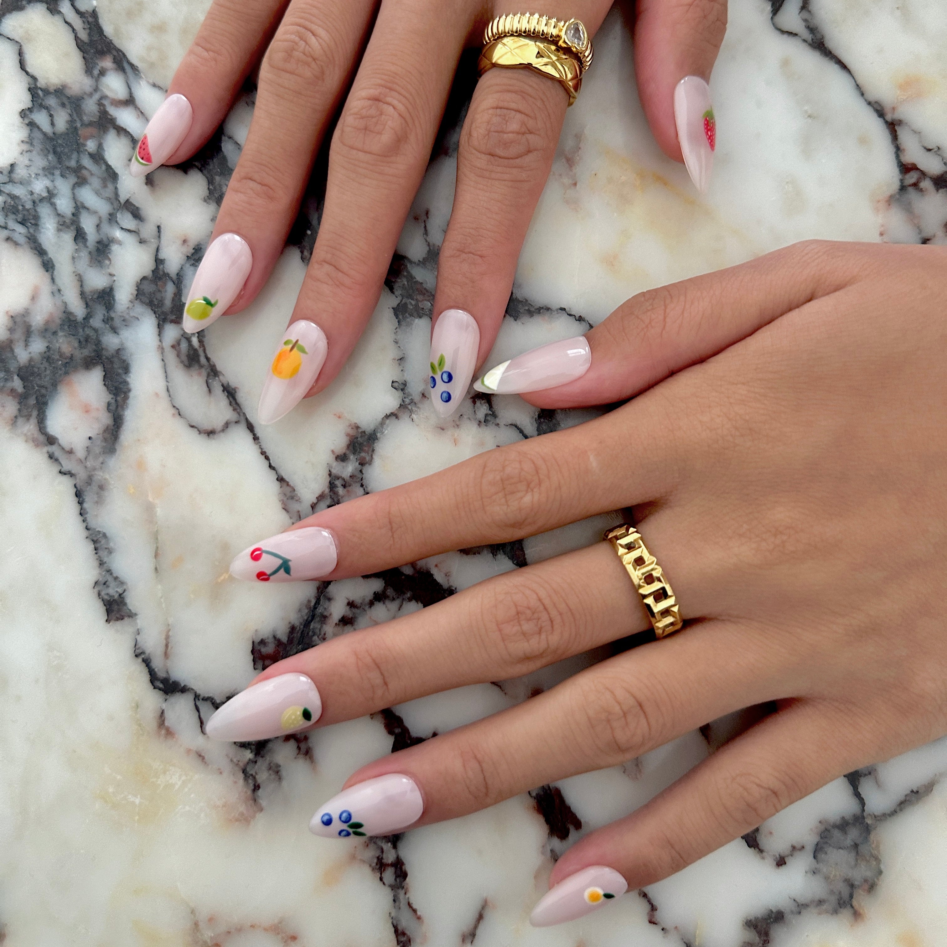 Close-up of hands with decorative nail art on a marble surface