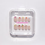 Set of decorative false nails in a clear plastic case on a white background
