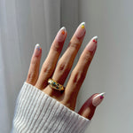 Hand with decorative nails and a gold ring on a neutral background