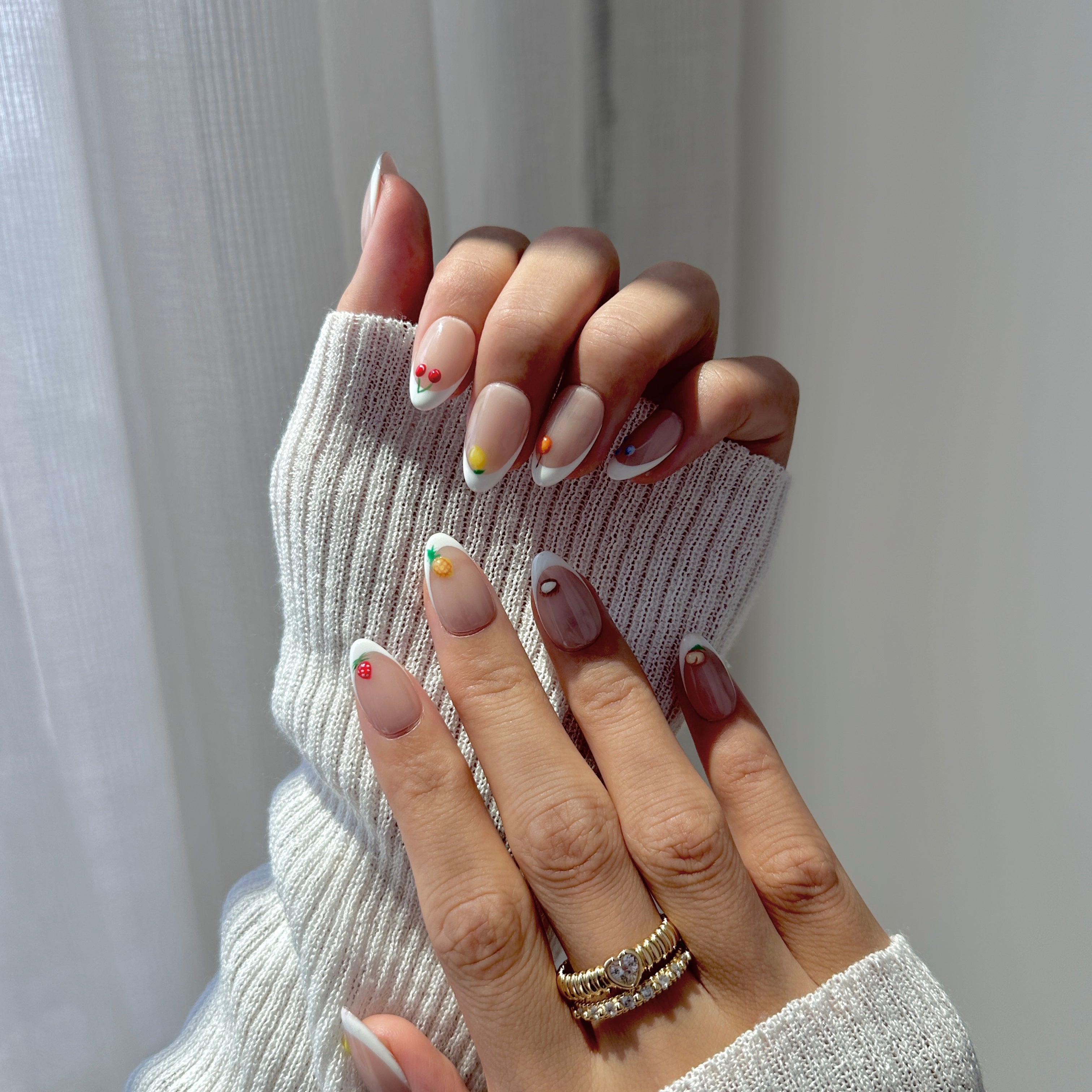 Close-up of a hand with stylish nail art wearing a white textured sleeve.