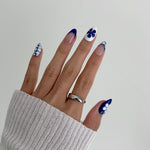 Hand with blue and white nail design on a plain background