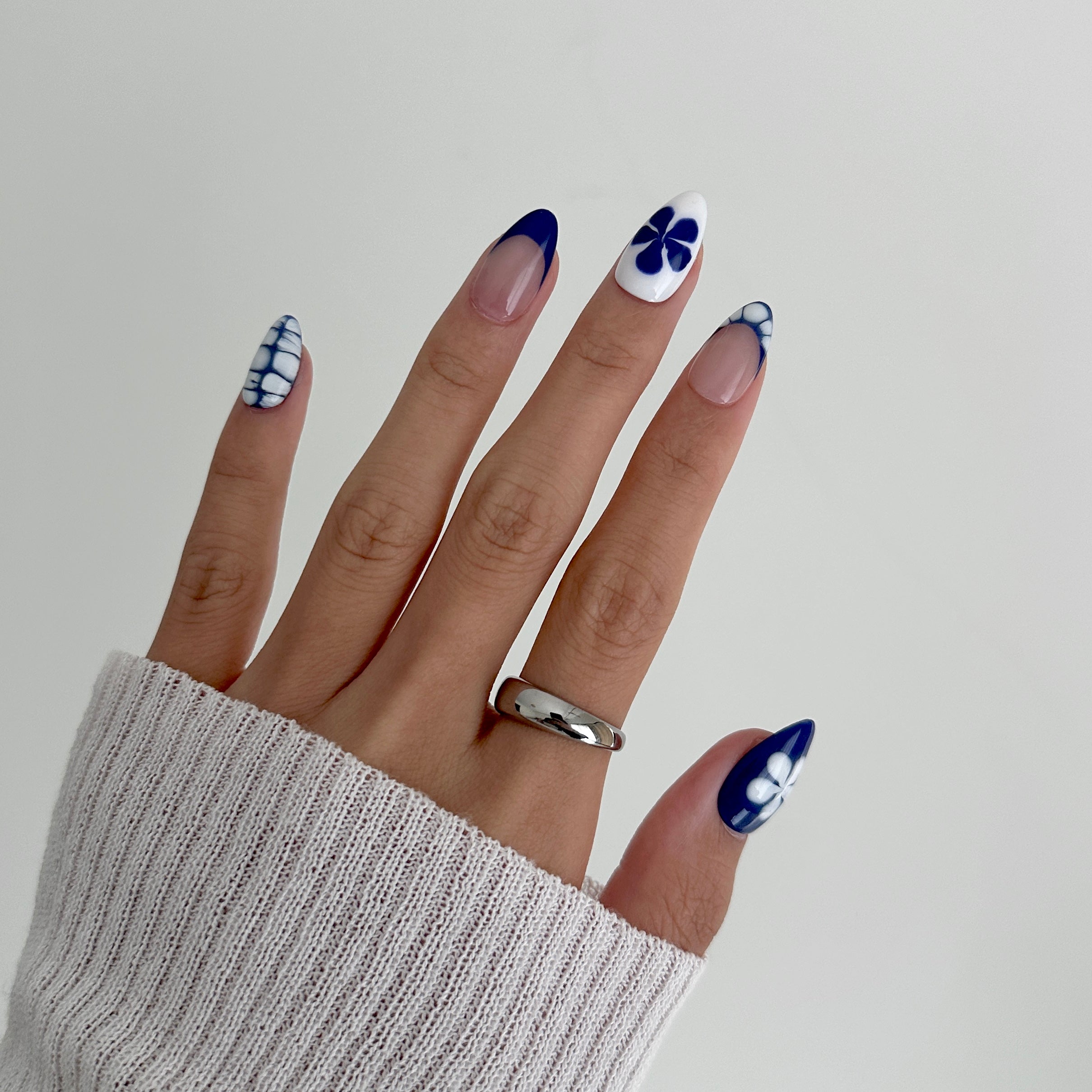 Hand with blue and white nail design on a plain background