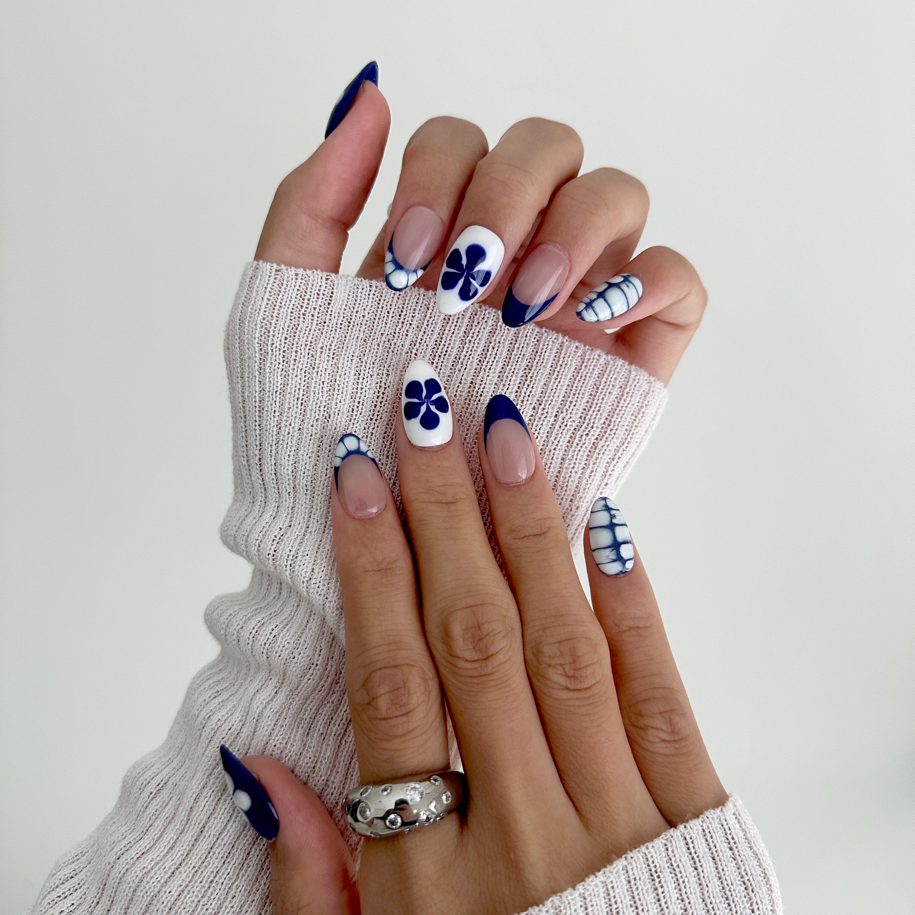 Close-up of hands with floral nail design on a white background
