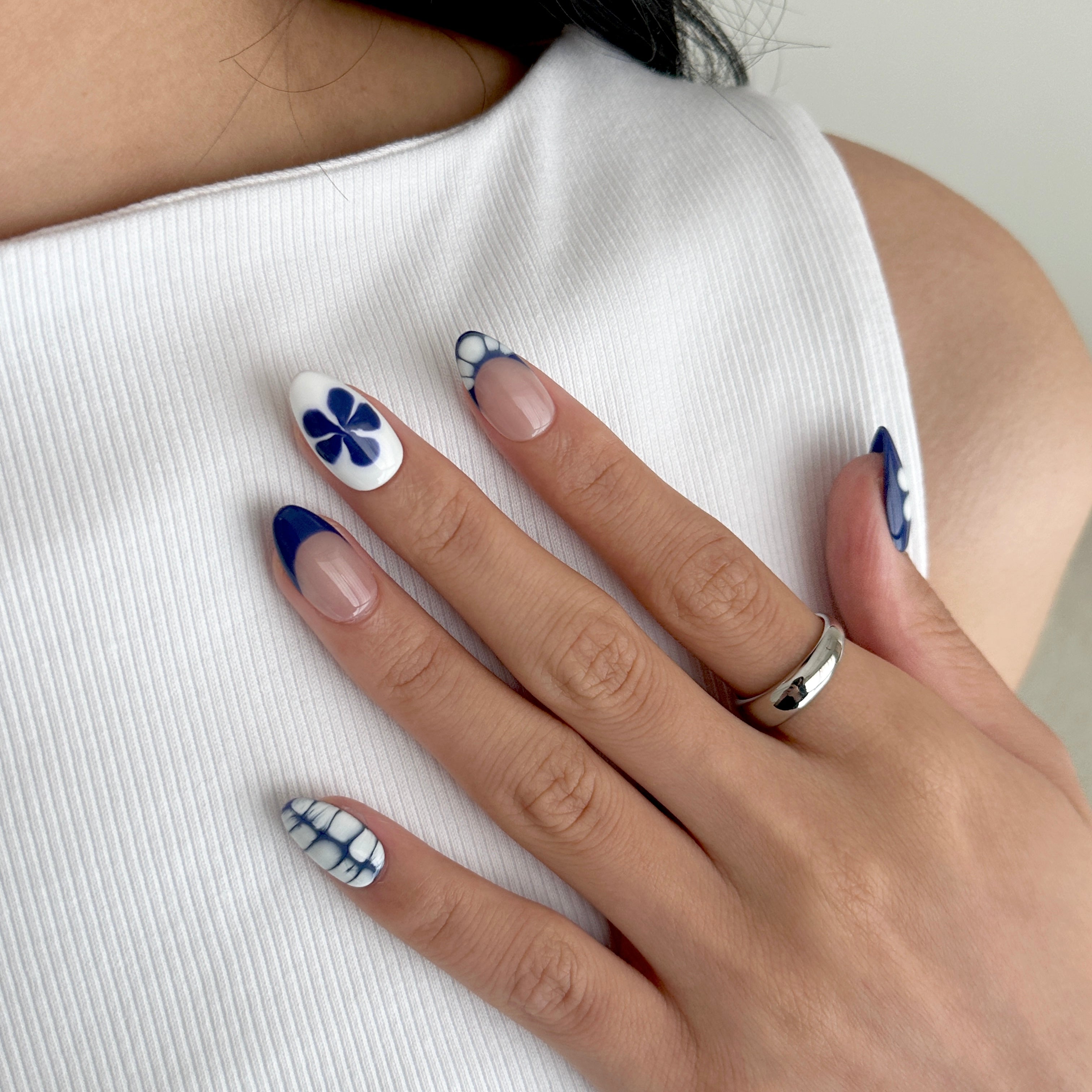 Hand with blue and white nail art on a white background