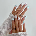 Close-up of a hand with decorative nails and rings on a neutral background