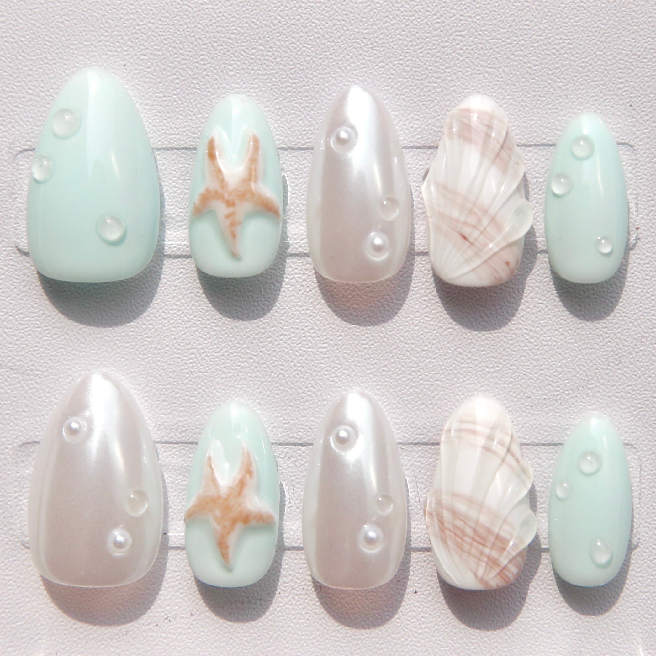 Set of nail art designs with sea-themed elements on a light background