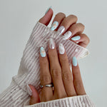 Close-up of hands with decorative nail art holding a textured white fabric.