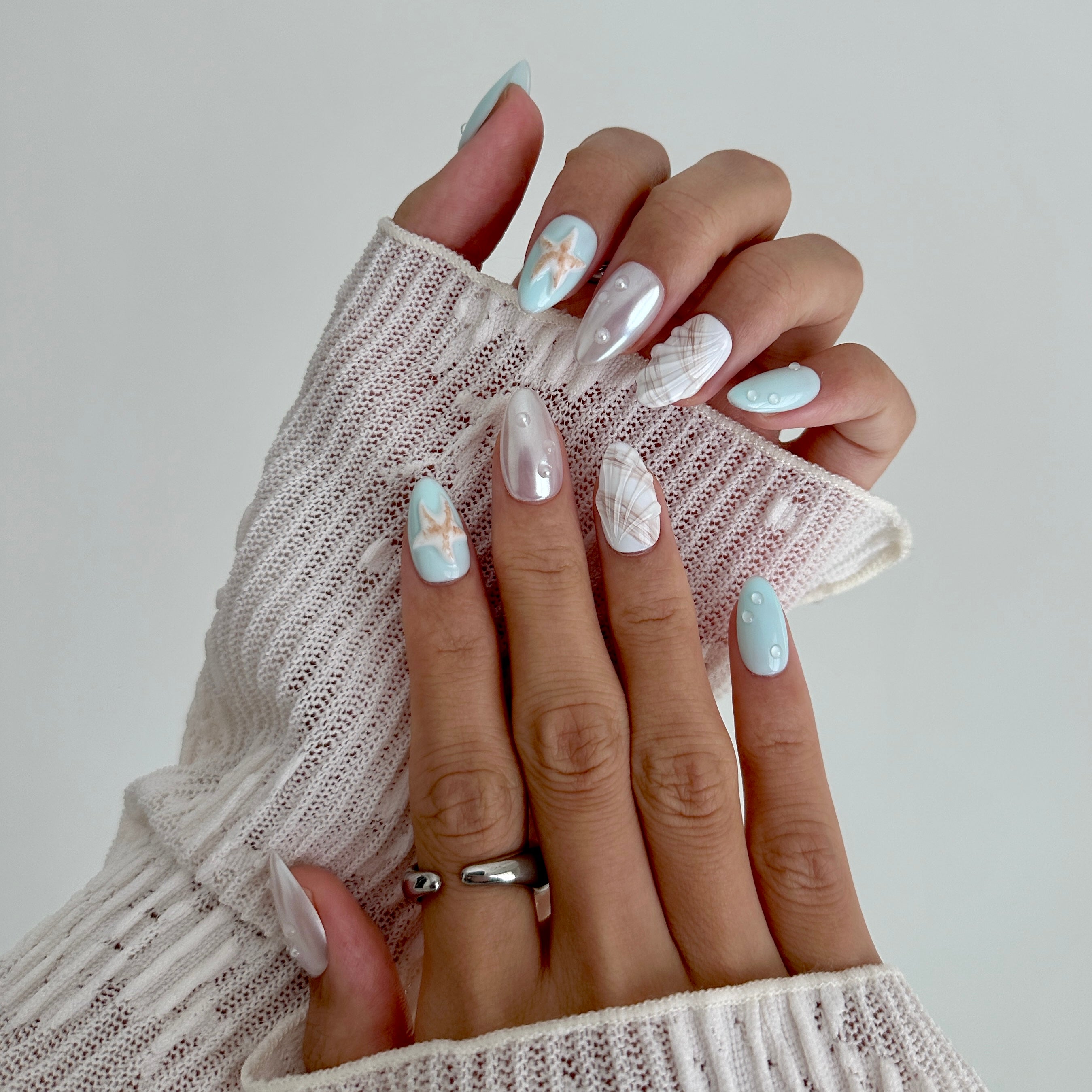 Close-up of hands with decorative nail art holding a textured white fabric.