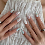 Close-up of hands with decorative nail art on a textured fabric background