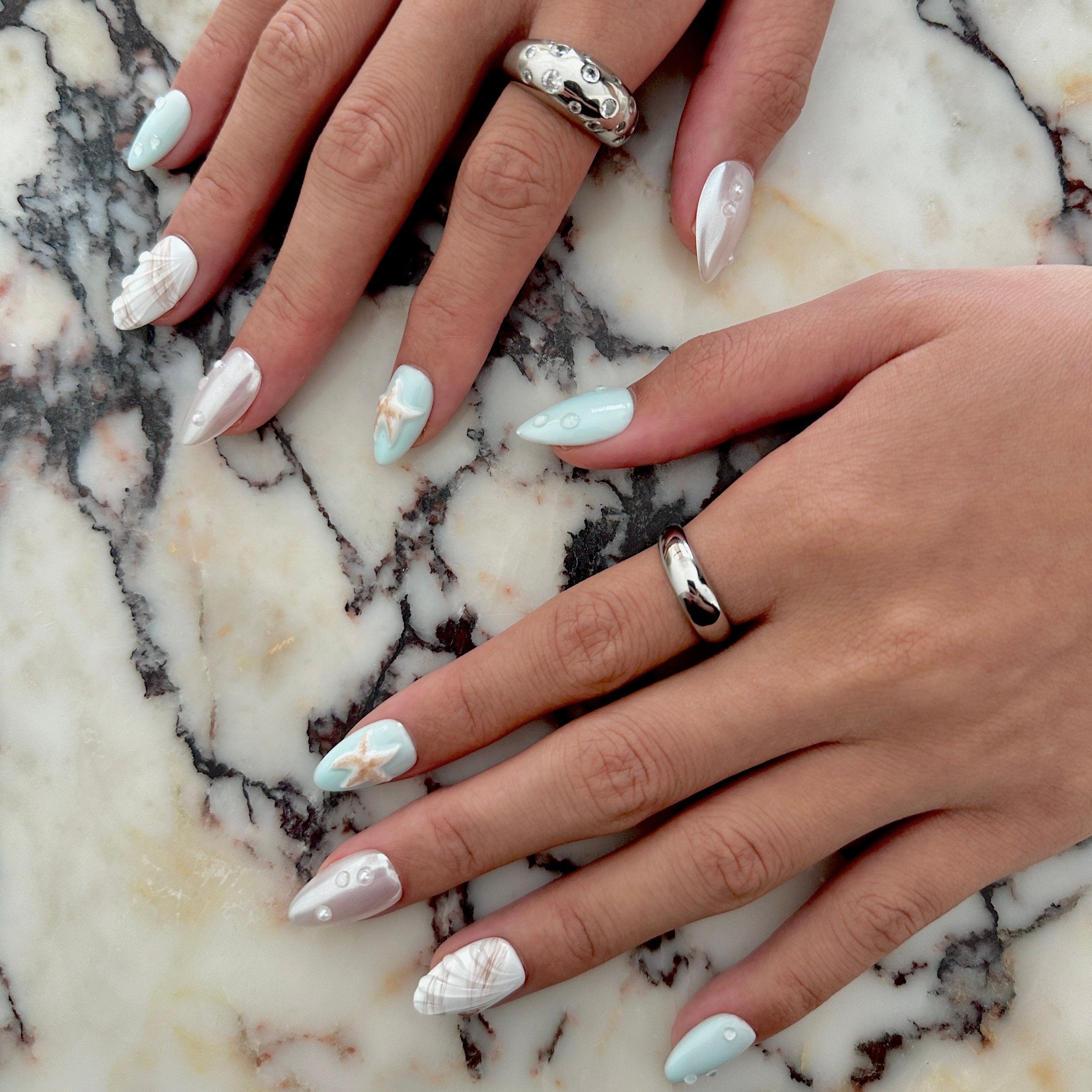 Close-up of hands with marble nail polish on a marble surface